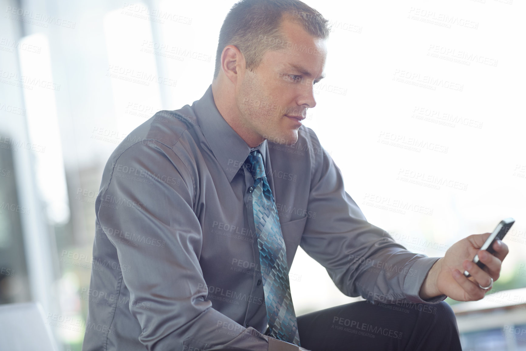 Buy stock photo A young caucasian businessman using a smartphone to send a text message