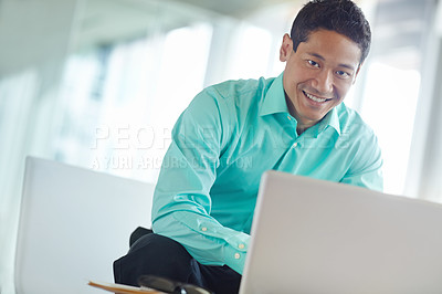 Buy stock photo Handsome young asian businessman using his laptop while at work