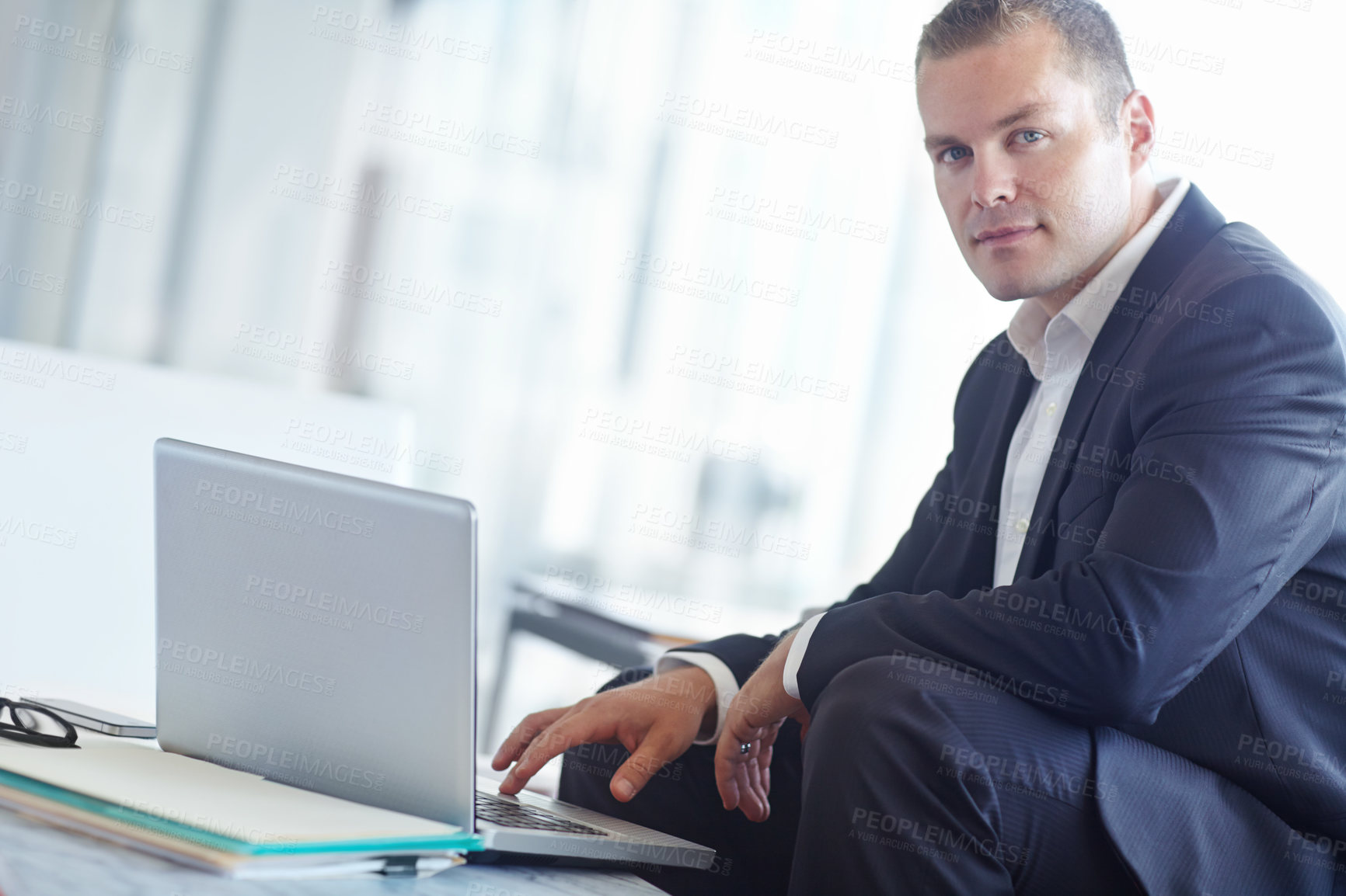 Buy stock photo A handsome young caucasian businessman working on his laptop