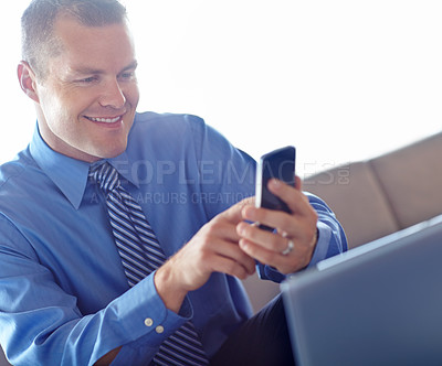 Buy stock photo Laptop, phone and smile with business man in lobby of office for contact or text message. Computer, reading or typing with happy professional employee in workplace for break or internet research