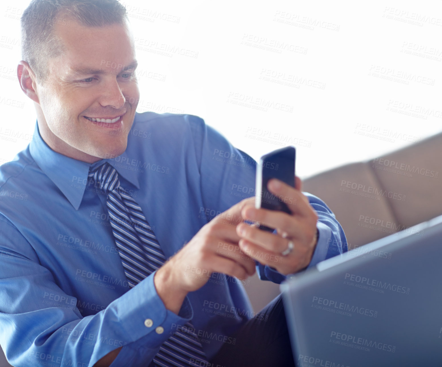 Buy stock photo Laptop, phone and smile with business man in lobby of office for contact or text message. Computer, reading or typing with happy professional employee in workplace for break or internet research