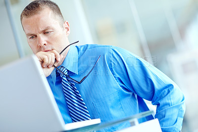 Buy stock photo Thoughtful young caucasian businessman working on his laptop 