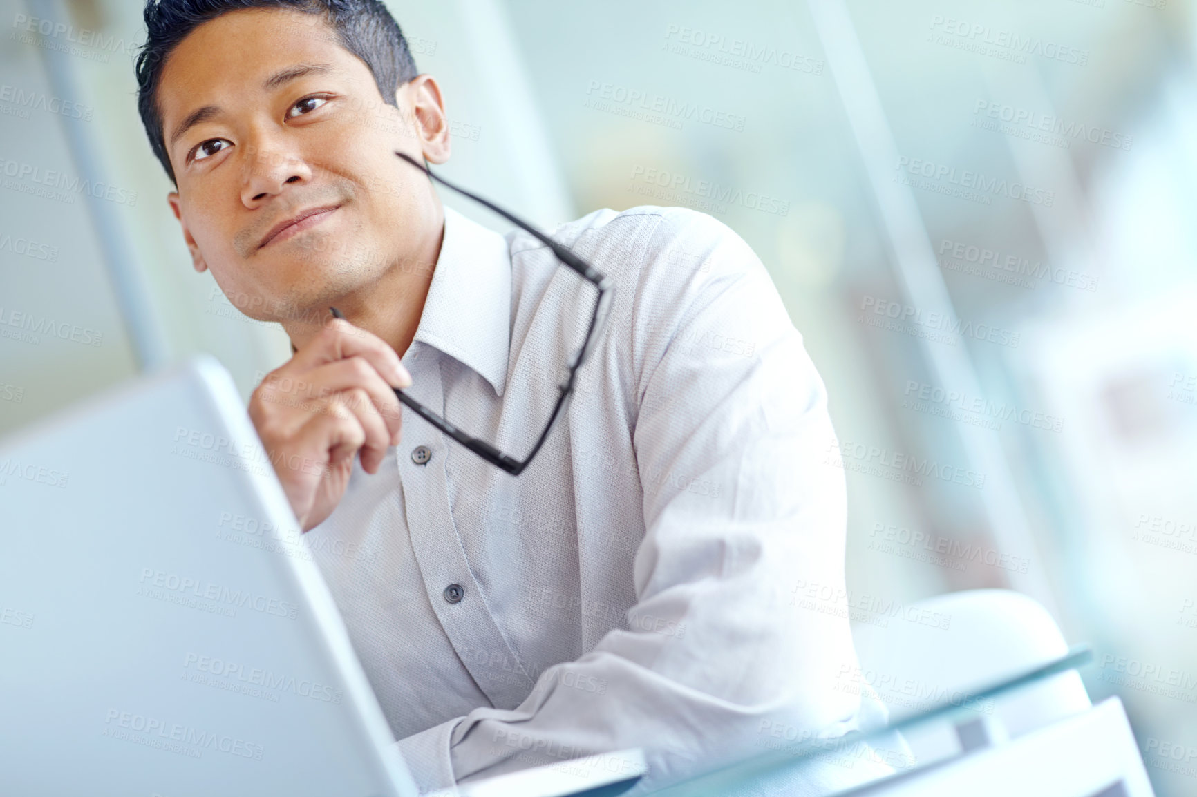 Buy stock photo Thoughtful young asian businessman working on his laptop 