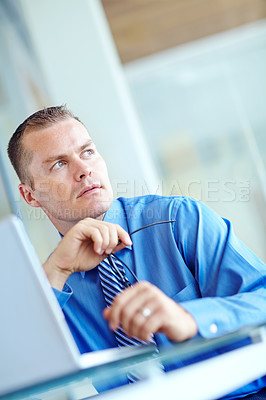 Buy stock photo Thoughtful young caucasian businessman working on his laptop 