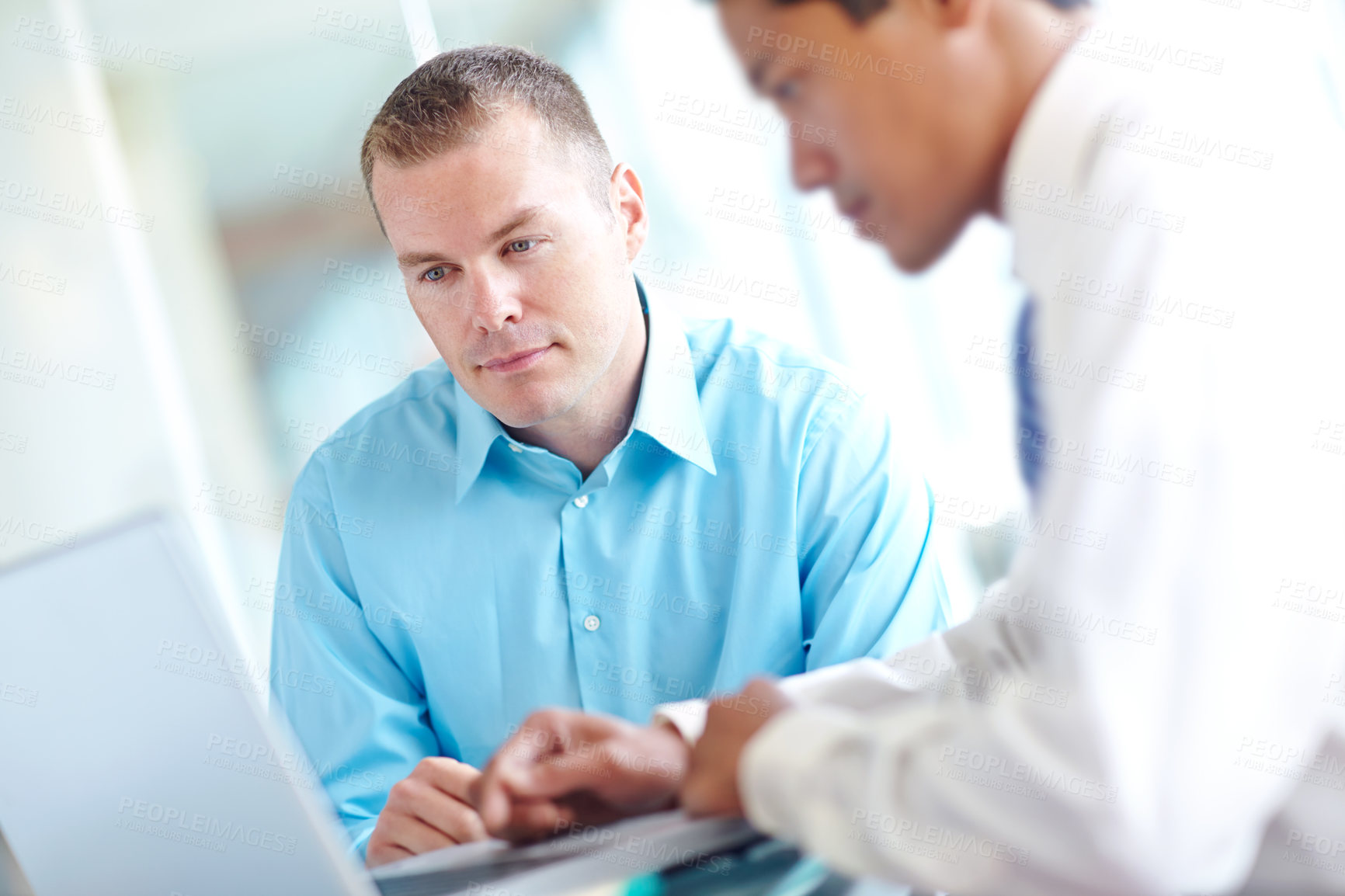 Buy stock photo Two handsome young businessmen working together while sharing a laptop between them