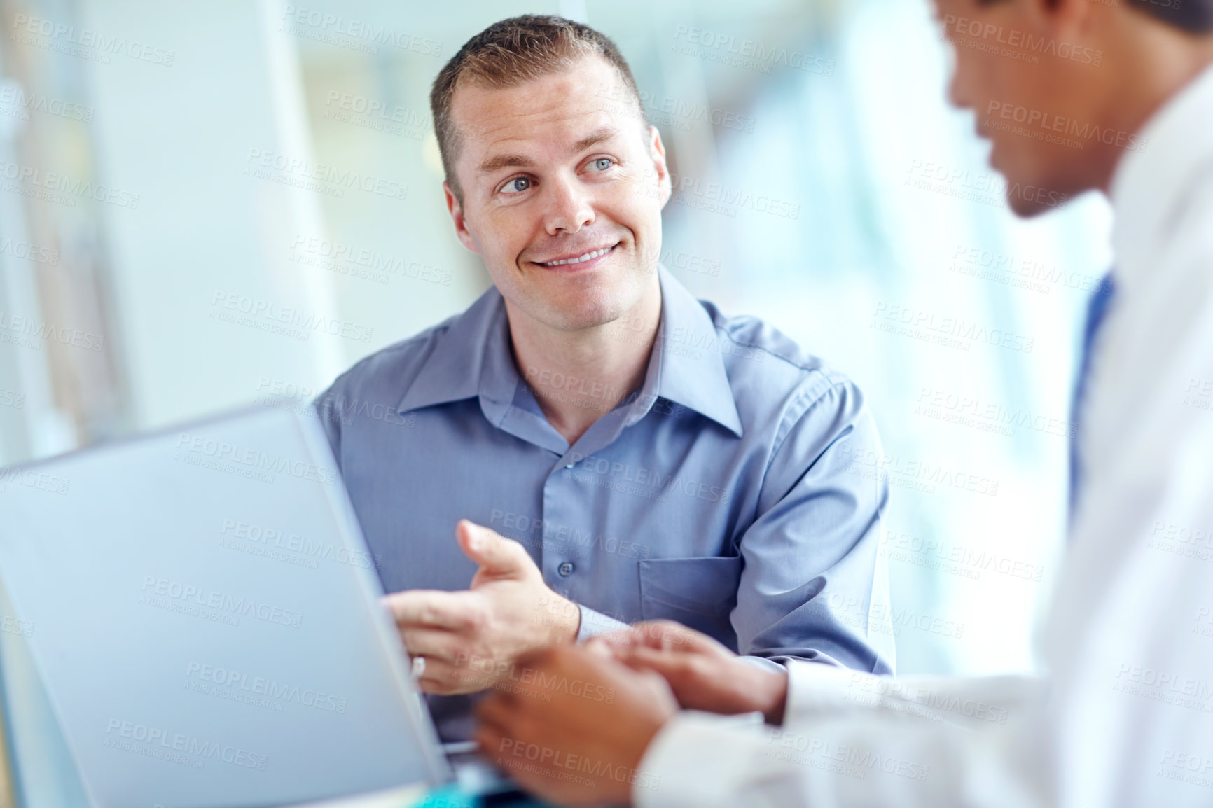 Buy stock photo Two handsome young businessmen working together while sharing a laptop between them