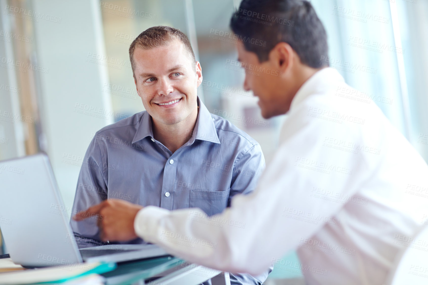 Buy stock photo Two handsome young businessmen working together while sharing a laptop between them