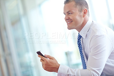 Buy stock photo A smiling caucasian businessman using a smartphone wile working