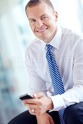 Buy stock photo A smiling caucasian businessman using a smartphone wile working