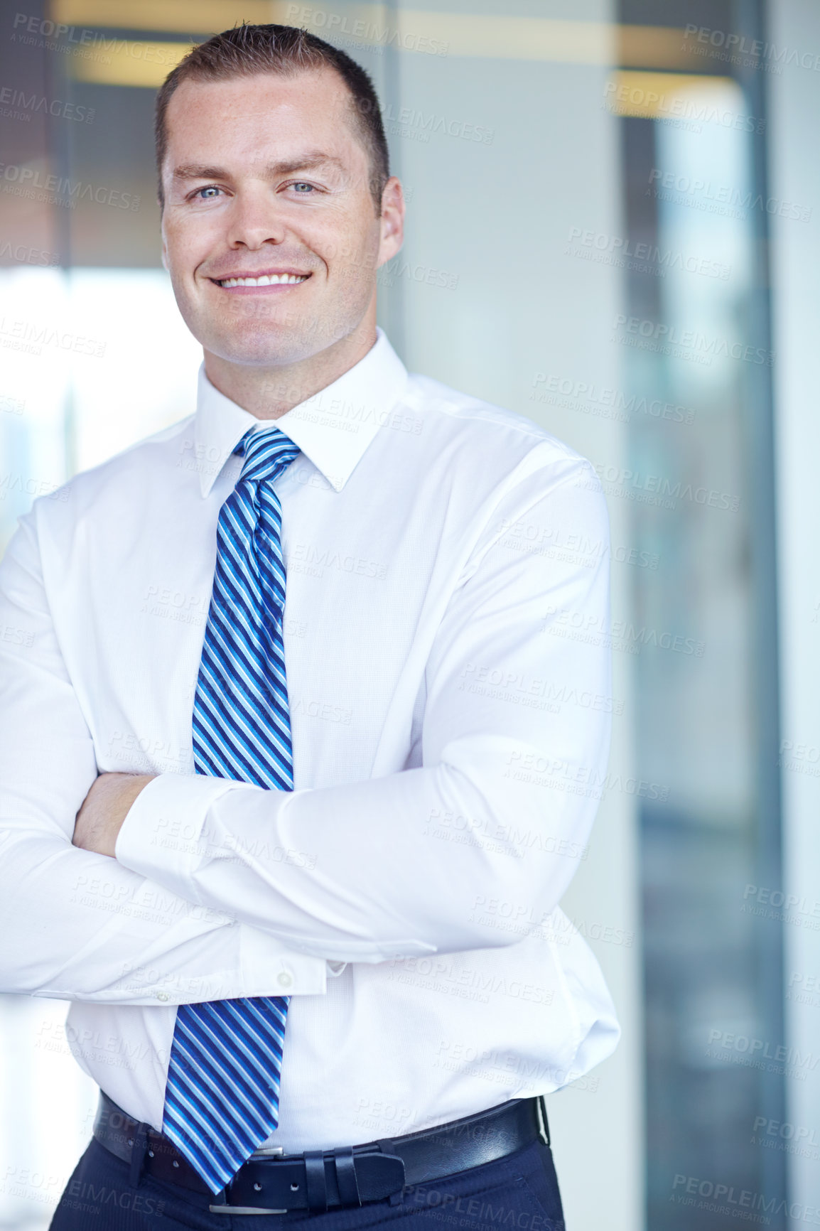 Buy stock photo Smiling caucasian businessman standing at work with his arms folded