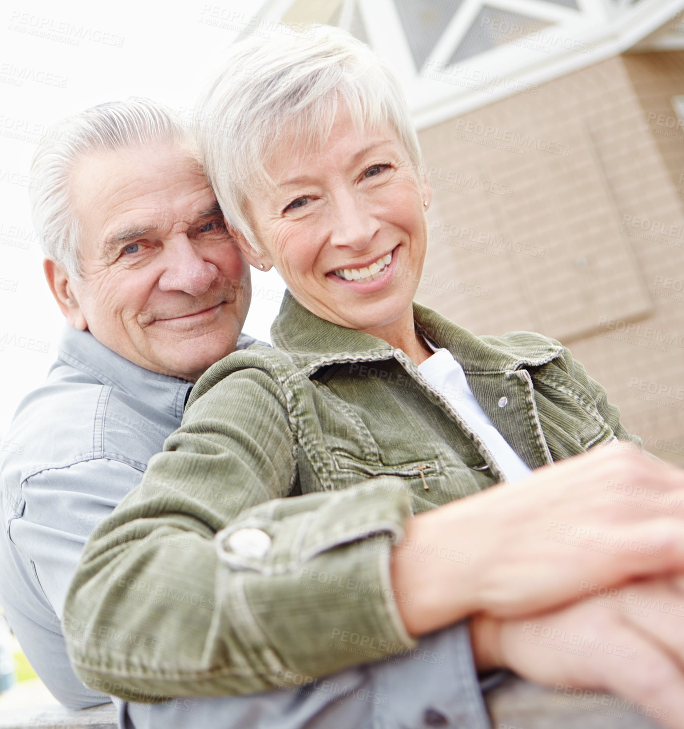 Buy stock photo Portrait of a mature couple sitting on a bench together and smiling at the camera