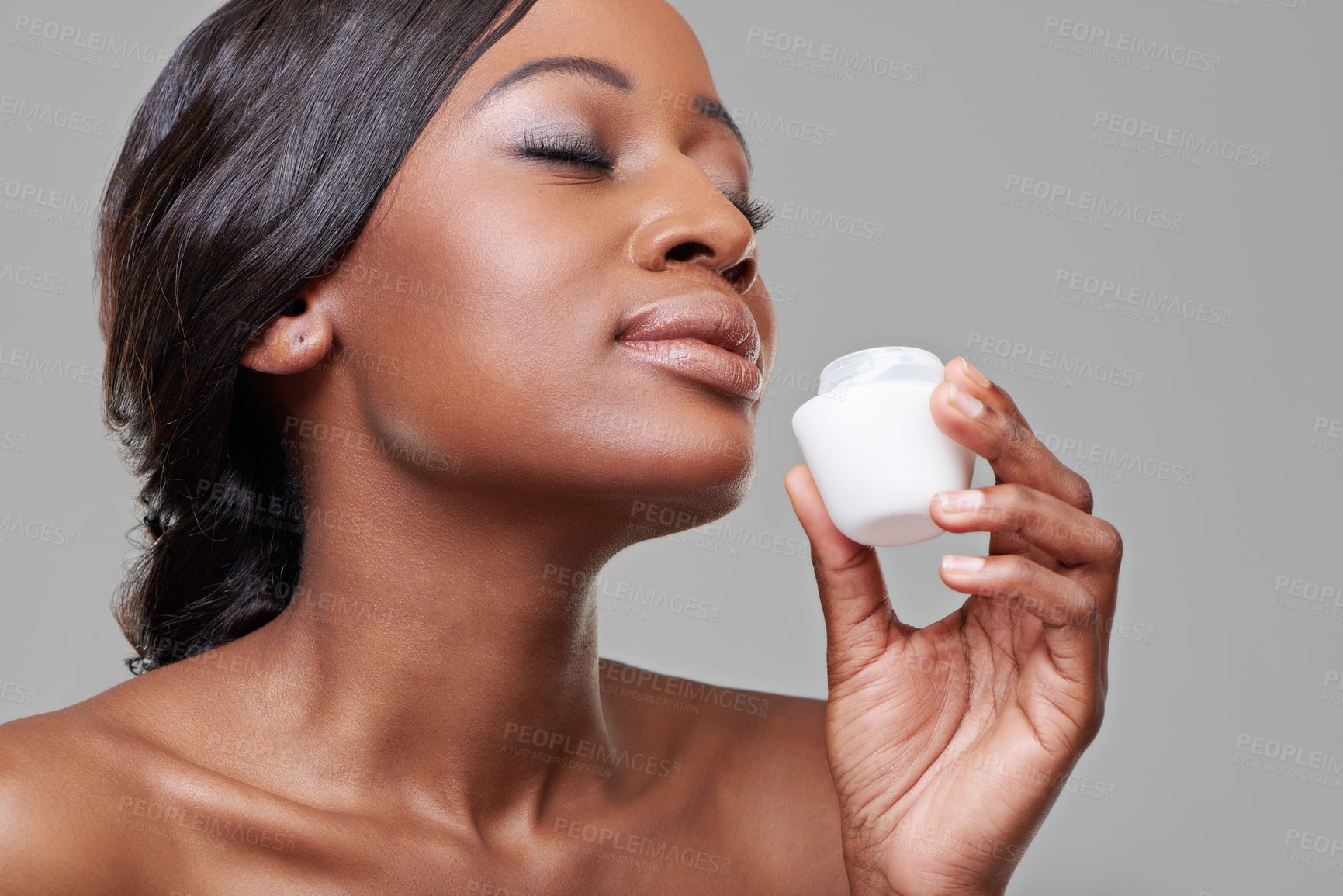 Buy stock photo Cropped studio shot of a beautiful young woman smelling her moisturizing cream