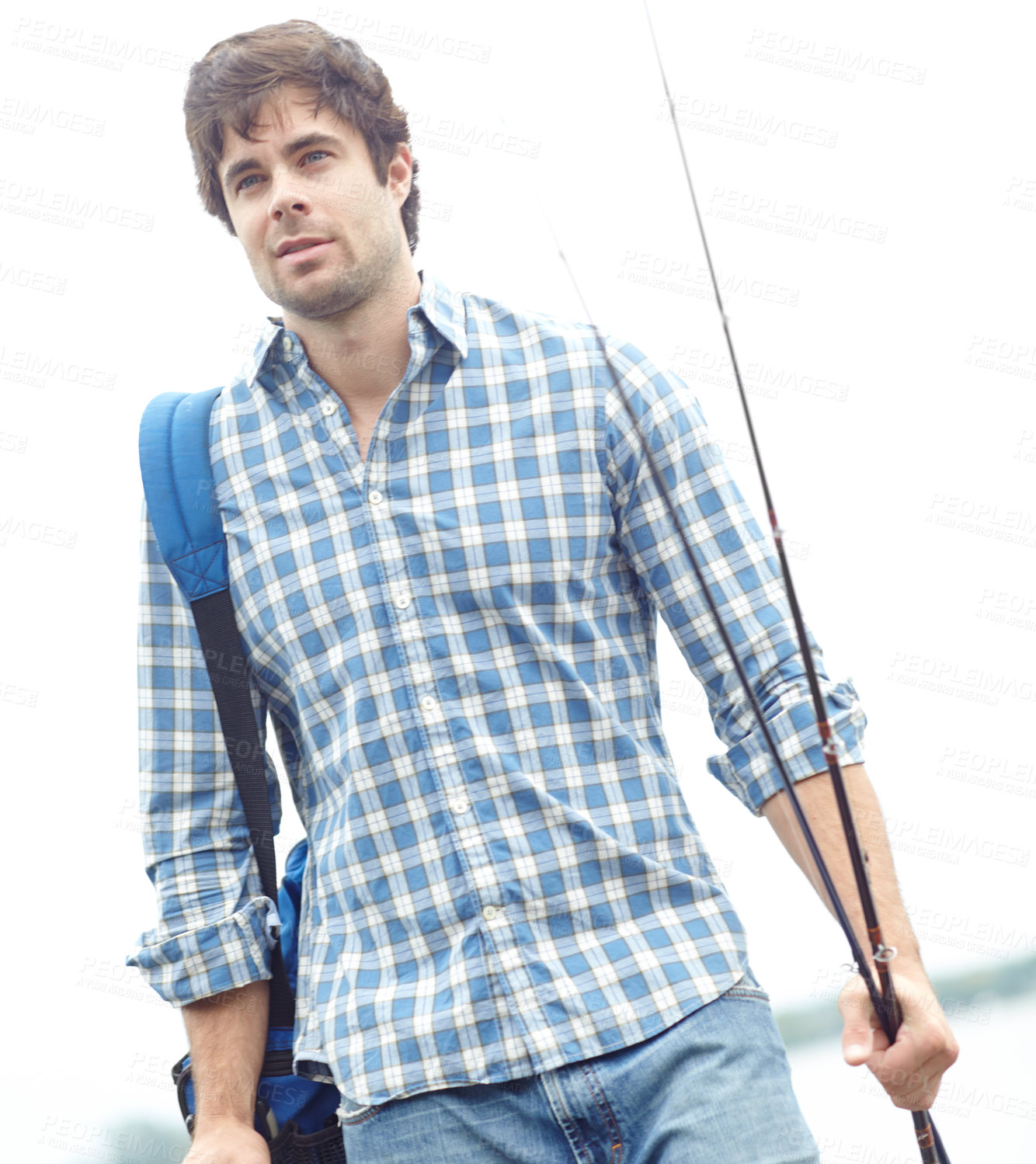 Buy stock photo A handsome young fisherman standing at the lake while carrying his gear