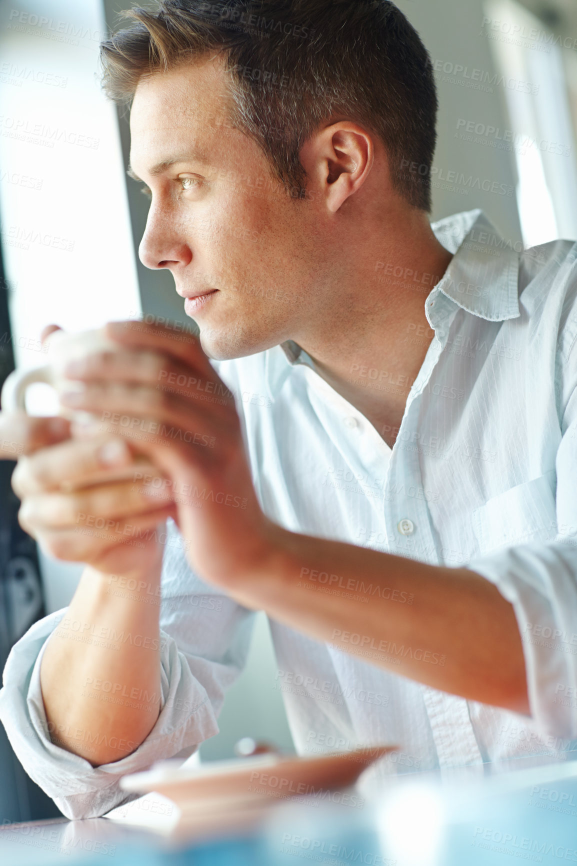 Buy stock photo A young man musing over a cup of coffee