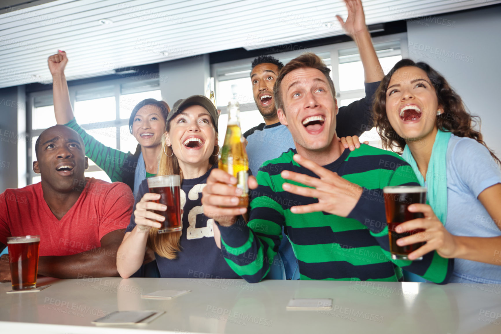 Buy stock photo A group of friends cheering on their favourite team at the bar