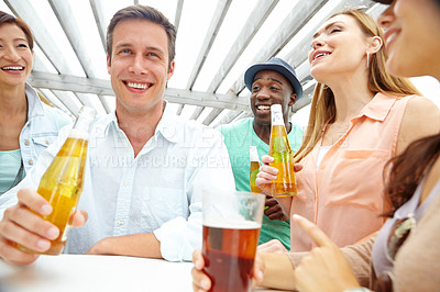 Buy stock photo A handsome young man enjoying drinks on the outdoors deck of a restaurant with friends