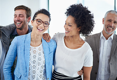 Buy stock photo Portrait of two female coworkers smiling in an office with colleagues in the background