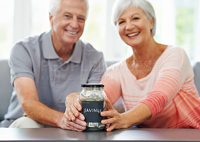 Buy stock photo Shot of a senior couple proudly posing with their savings jar