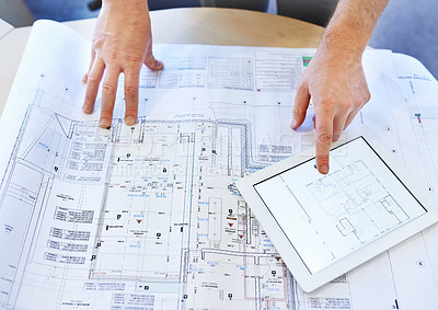 Buy stock photo Shot of an architects hands examining blueprints and using a digital tablet