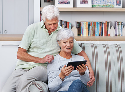 Buy stock photo A senior couple relaxing in their home with a digital tablet