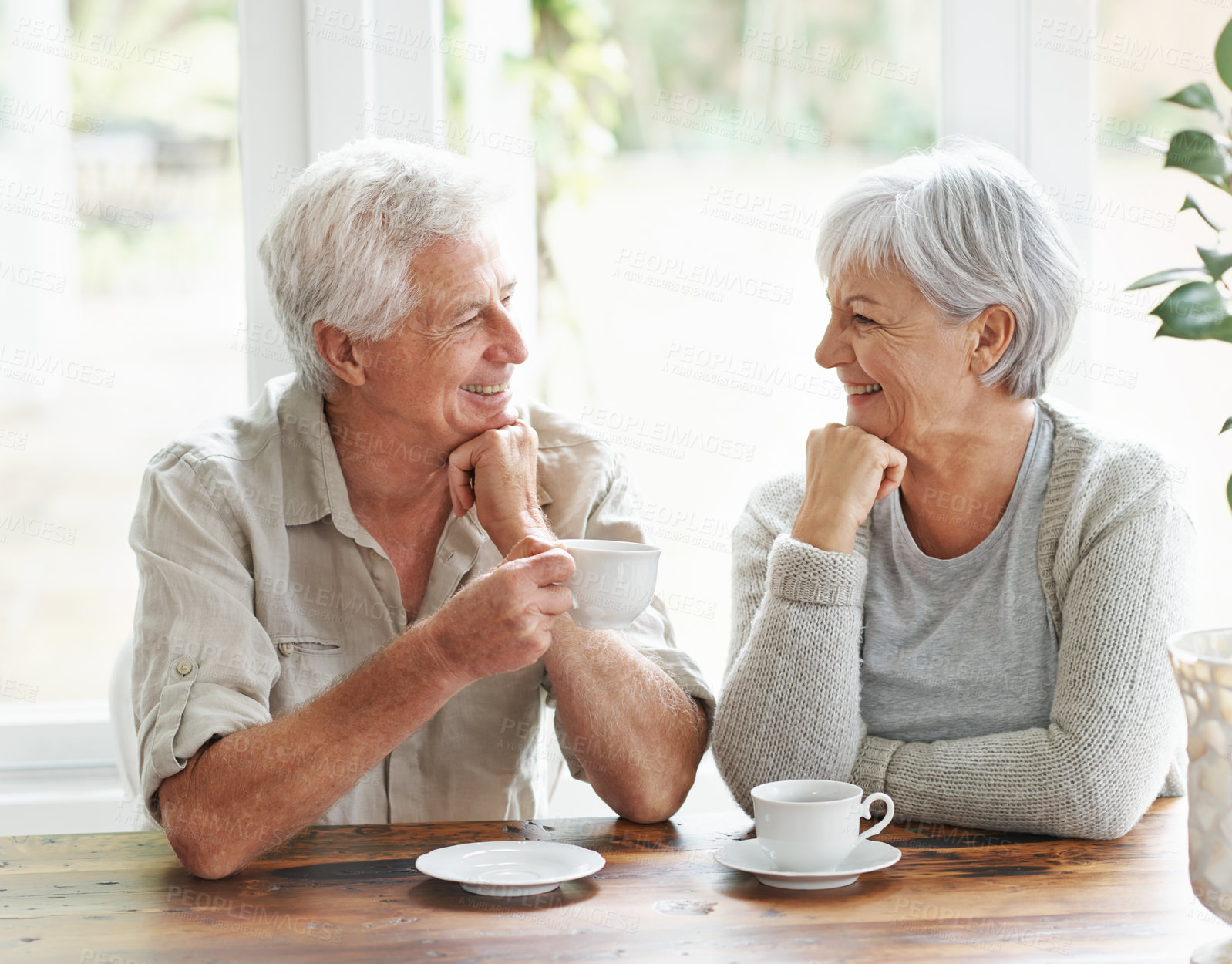 Buy stock photo Happy senior couple, coffee and smile for morning breakfast, relationship or bonding together at home. Elderly man and woman smiling with drinking tea cup or mug in relax, conversation or retirement