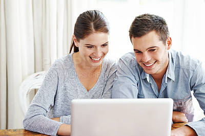 Buy stock photo A young couple using a laptop together at home