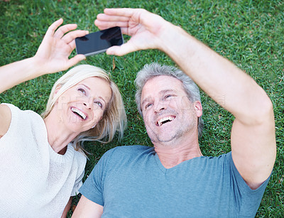 Buy stock photo A happy mature couple taking a picture of themselves with a smartphone