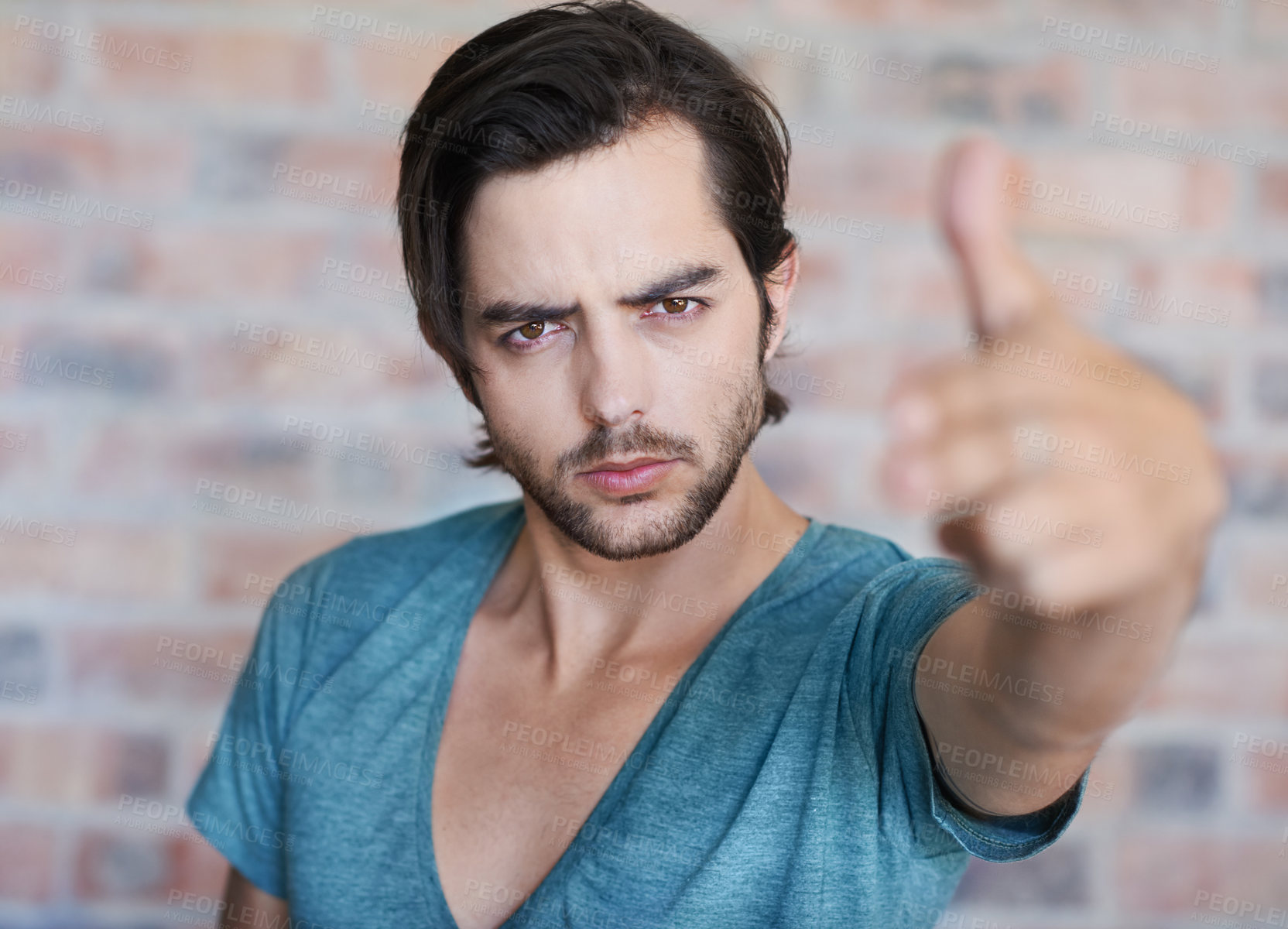 Buy stock photo Angry, portrait and man by brick wall with hand gun, confidence or edgy tshirt in Germany. Male person, face or cool model with violence gesture for shooting weapon, pistol fingers or self defence