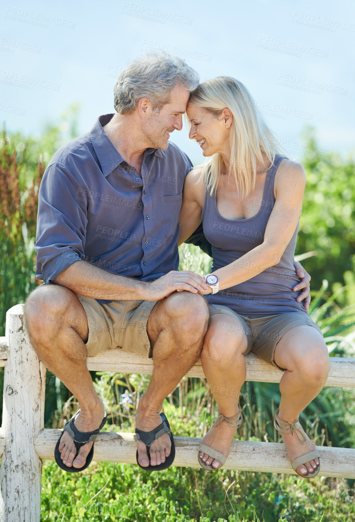 Buy stock photo Outdoor, embrace and couple on fence, countryside and bonding for holiday in nature, romance and love. Summer, travel and vacation for people, woman and man with smile, hug and happy together