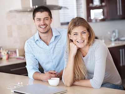 Buy stock photo Portrait of a smiling couple sitting in their kitchen with a laptop and cup of coffee infront of them