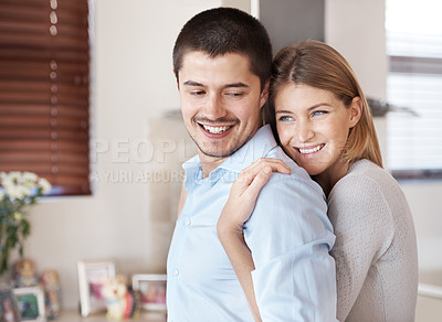 Buy stock photo A smiling couple in their kitchen embracing each other with copyspace