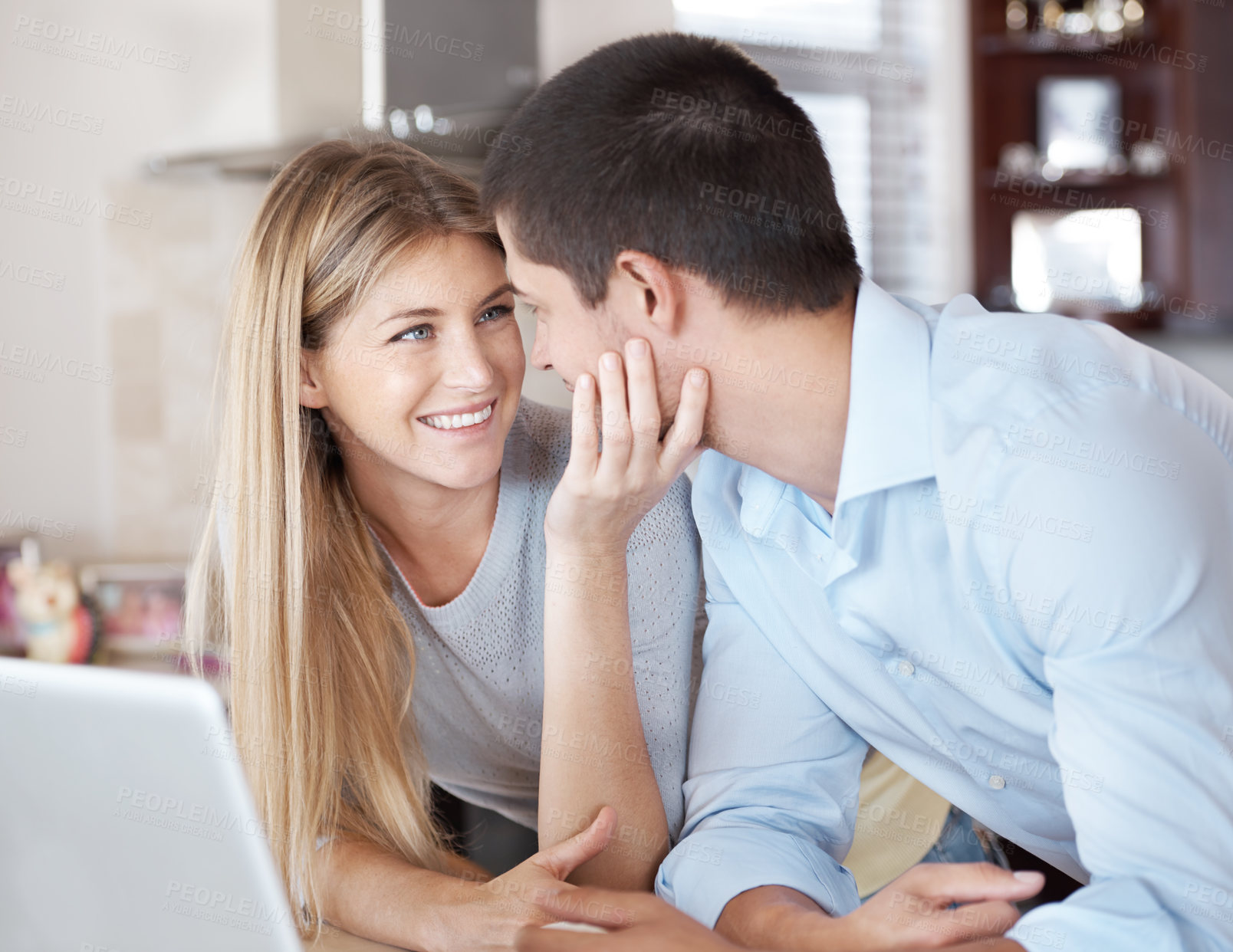 Buy stock photo A loving girlfriend affectionately holding her boyfriend's face while they look at each other with a laptop infront of them