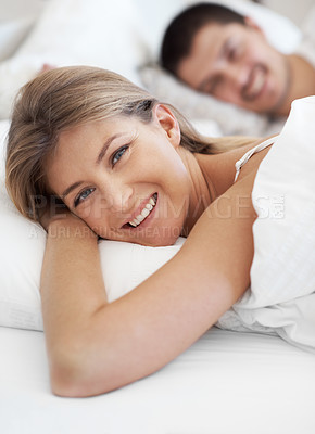 Buy stock photo Smiling young couple lying in bed together 