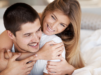 Buy stock photo Attractive young woman embracing her partner while they lie in bed together