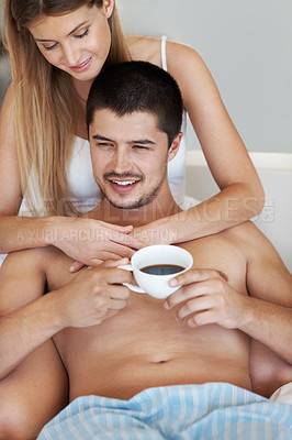 Buy stock photo Handsome young man enjoying some coffee in bed while relaxing with his partner
