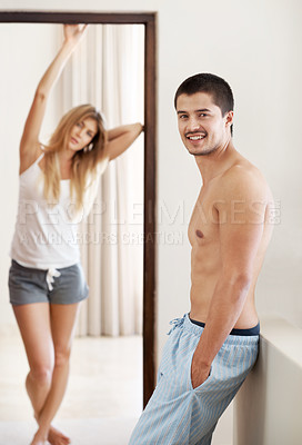 Buy stock photo Handsome pajama-clad man smiling with his partner in the background