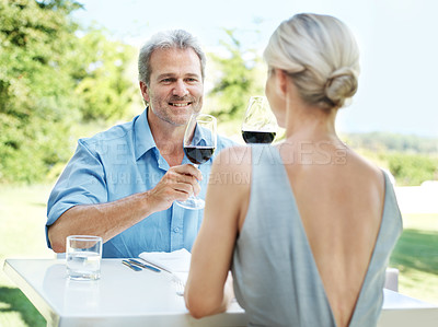 Buy stock photo Happy mature couple toasting their love with two glasses of wine while outdoors