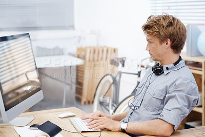 Buy stock photo  Business man typing on a computer keyboard and sitting at a desk in his office. Male web developer at his workplace. Entrepreneur working and sending emails. Serious businessman looking at a screen