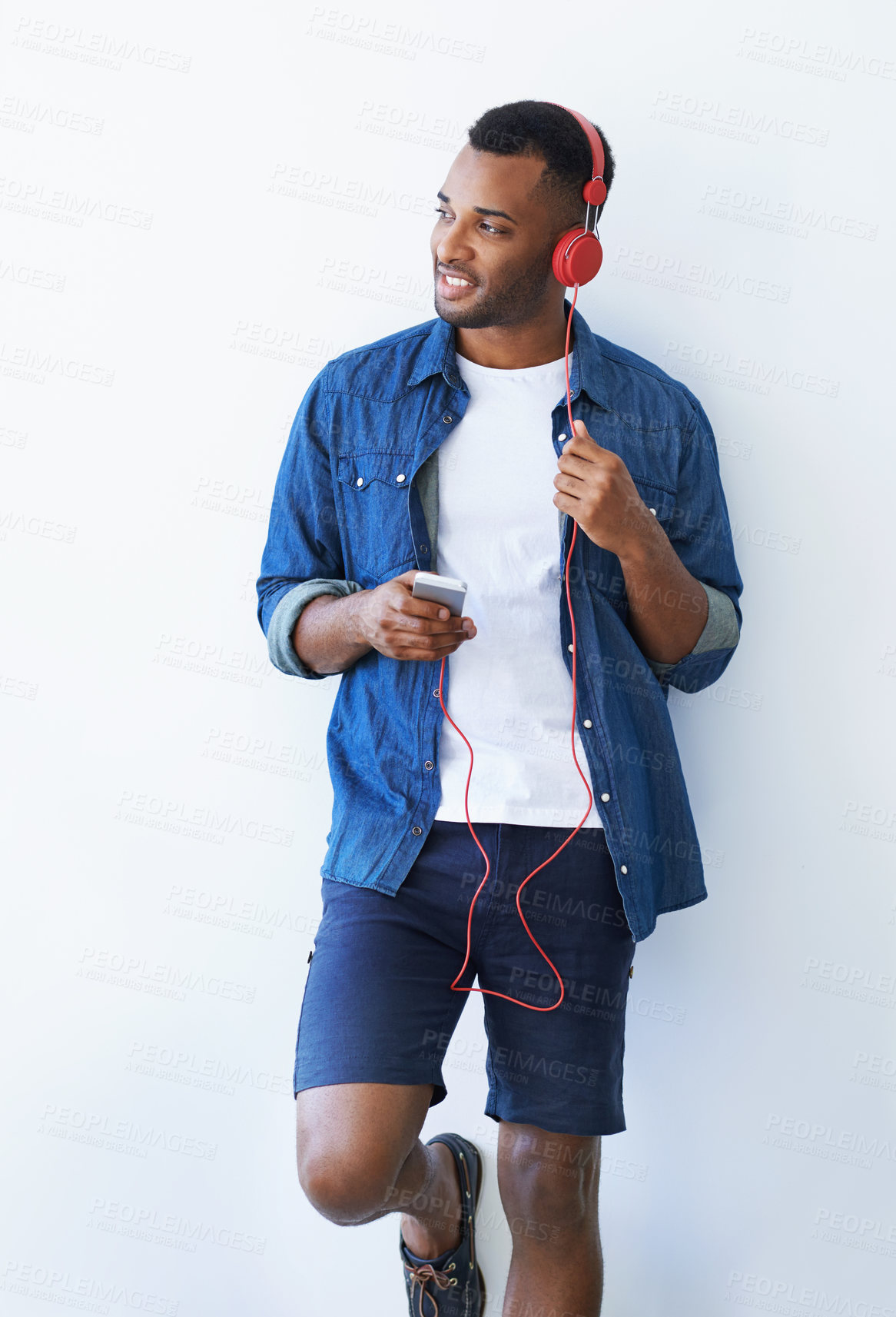 Buy stock photo Black man, smartphone and headphones for radio by wall, idea and choice for streaming by white background. Playlist curator, person or tech for art, mockup space and review with music on mobile app