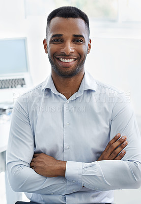 Buy stock photo A handsome young african american businessman sitting at his desk with his arms folded
