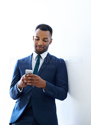 Buy stock photo A handsome african american businessman using his smartphone while indoors