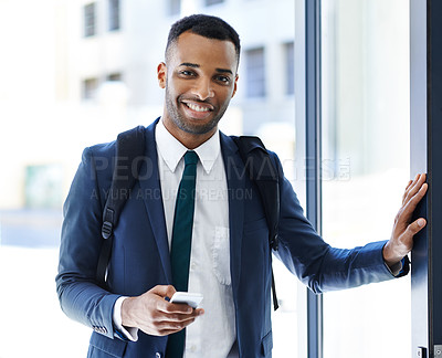 Buy stock photo A handsome african american businessman using his smartphone while indoors