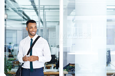 Buy stock photo A handsome young african american businessman using his smartphone while in the office