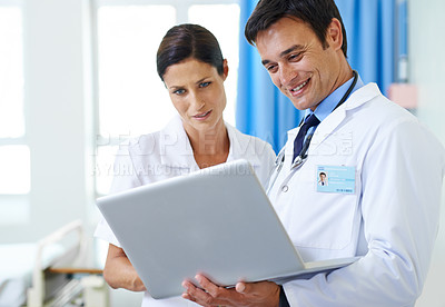 Buy stock photo Shot of a doctor and nursing assistant looking at a laptop together