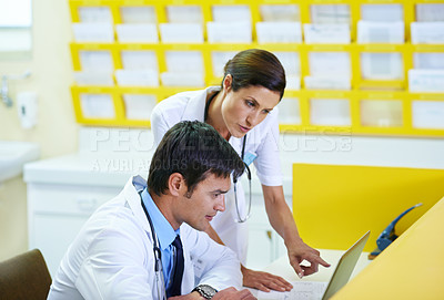 Buy stock photo Shot of a handsome young doctor and his nursing assistant looking at a laptop screen