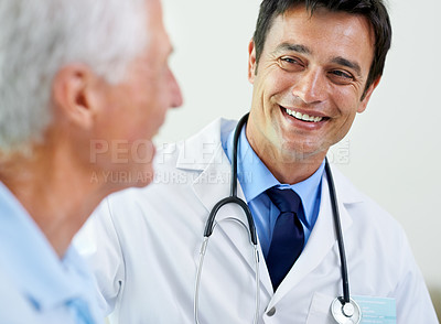 Buy stock photo Shot of a handsome young doctor delivering news to a senior patient