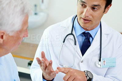Buy stock photo Shot of a handsome young doctor explaining the situation to a senior patient