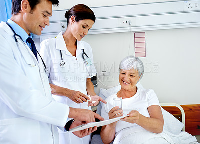 Buy stock photo Shot of two doctors attending their senior patient who is in a hospital bed