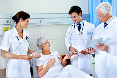 Buy stock photo Shot of three doctors attending a senior patient who is in a hospital bed
