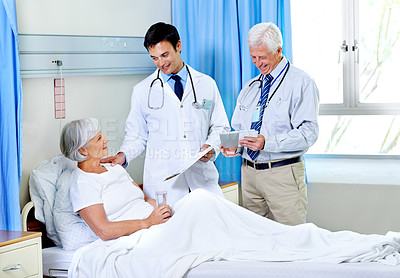 Buy stock photo Shot of two doctors attending a senior patient who is in a hospital bed